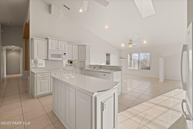 kitchen featuring white appliances, light countertops, arched walkways, and ceiling fan