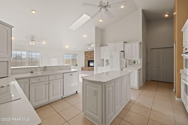 kitchen featuring white appliances, a skylight, a ceiling fan, and a sink