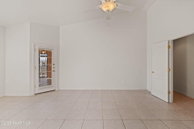 empty room featuring light tile patterned floors, a ceiling fan, and baseboards