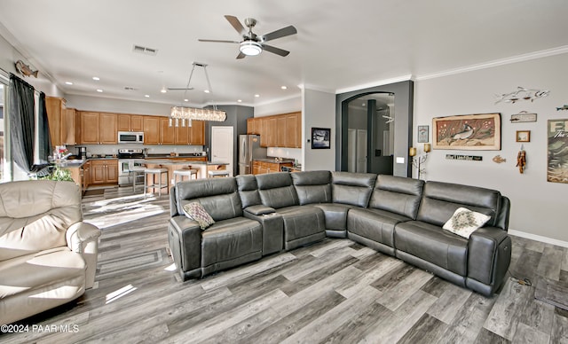 living room with ceiling fan, ornamental molding, and light hardwood / wood-style flooring