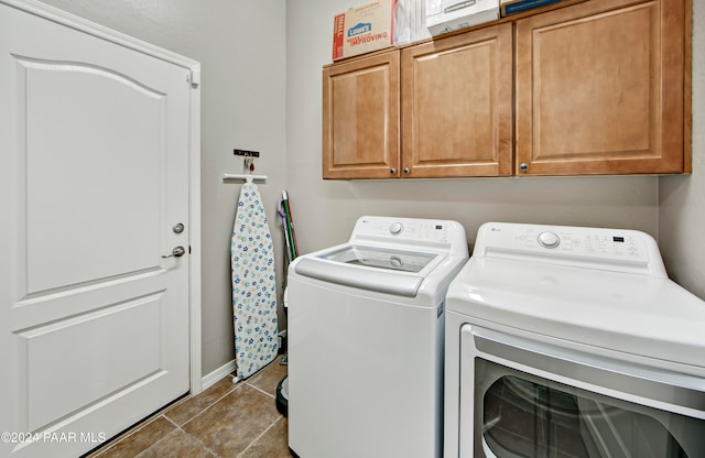 washroom with cabinets, washing machine and dryer, and dark tile patterned floors