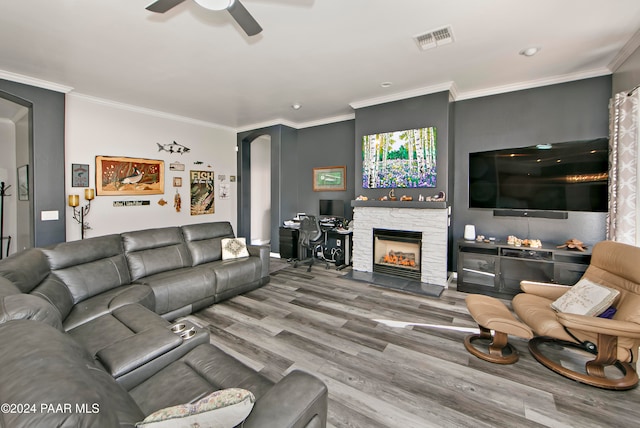 living room featuring hardwood / wood-style flooring, a fireplace, ceiling fan, and crown molding