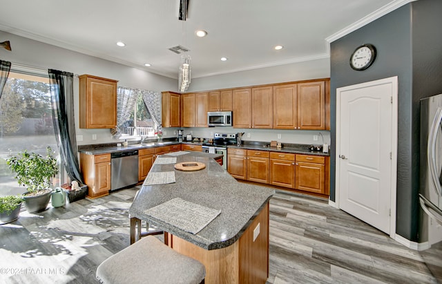 kitchen featuring a center island, stainless steel appliances, light hardwood / wood-style floors, decorative light fixtures, and ornamental molding