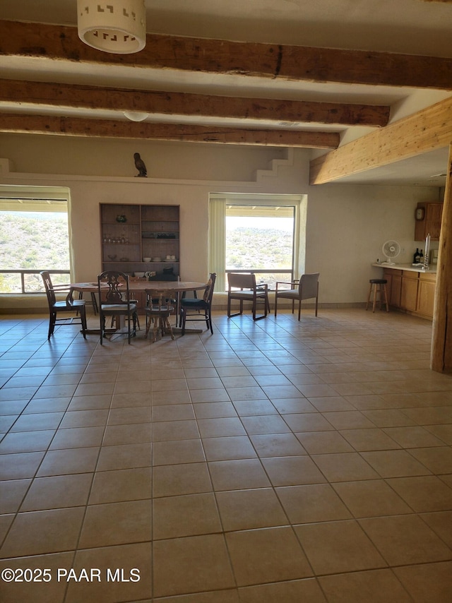 dining room with beam ceiling, a healthy amount of sunlight, and light tile patterned flooring