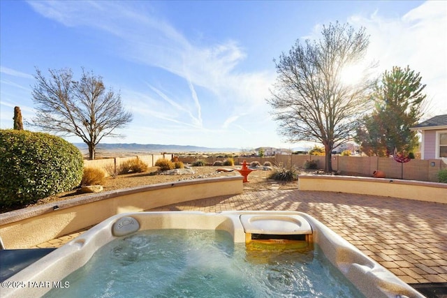 view of pool with a hot tub, a mountain view, and a patio