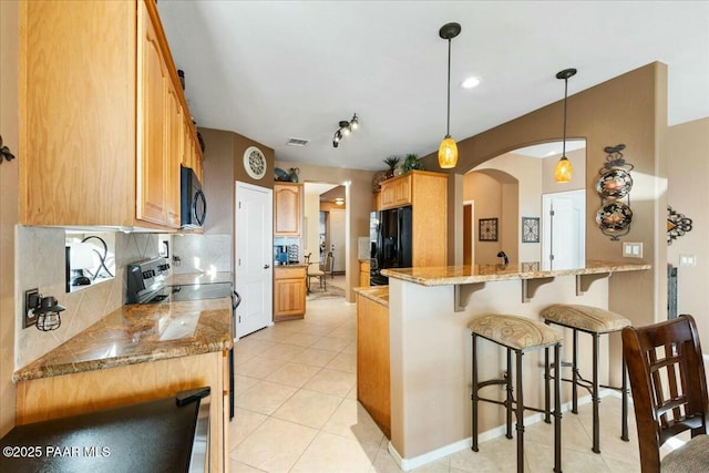 kitchen featuring light stone counters, black appliances, hanging light fixtures, kitchen peninsula, and backsplash