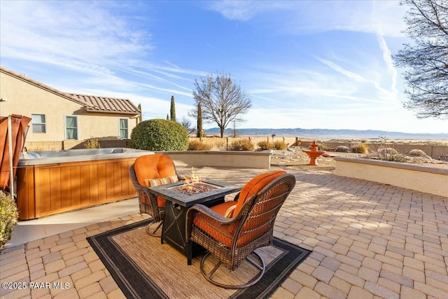 view of patio / terrace with a mountain view, a hot tub, and an outdoor fire pit