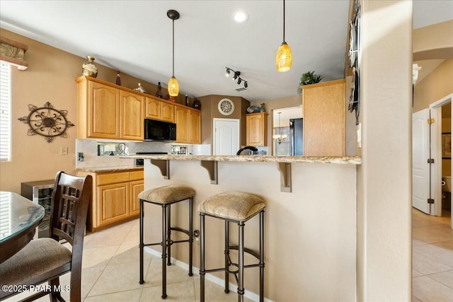 kitchen featuring light stone counters, tasteful backsplash, stainless steel refrigerator, and light tile patterned flooring