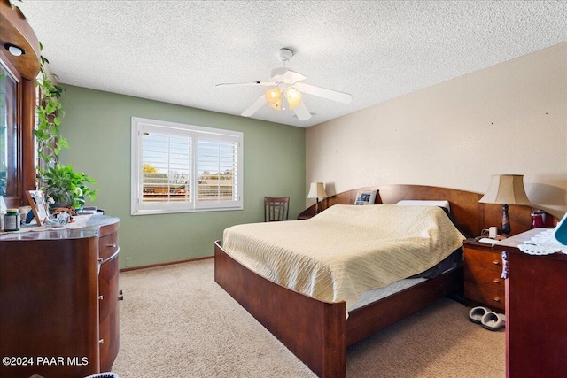 bedroom featuring a textured ceiling, ceiling fan, and light carpet