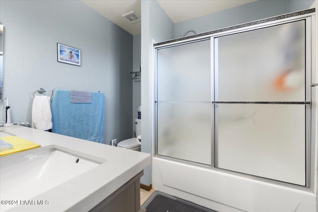 full bathroom featuring vanity, bath / shower combo with glass door, and toilet