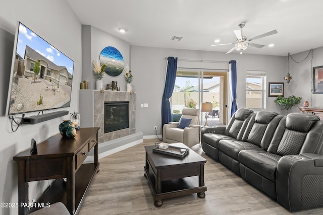 living room with a tiled fireplace, visible vents, light wood-style flooring, and recessed lighting