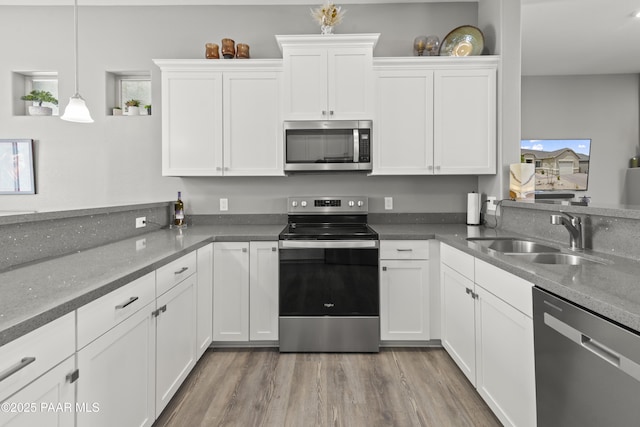 kitchen with appliances with stainless steel finishes, a wealth of natural light, white cabinetry, and a sink