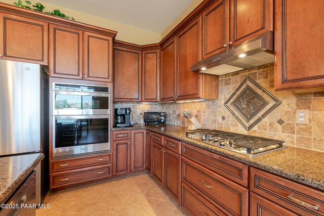 1646 Constable St, Prescott, AZ 86301 - kitchen featuring under cabinet range hood, appliances with stainless steel finishes, backsplash, stone counters, and brown cabinetry