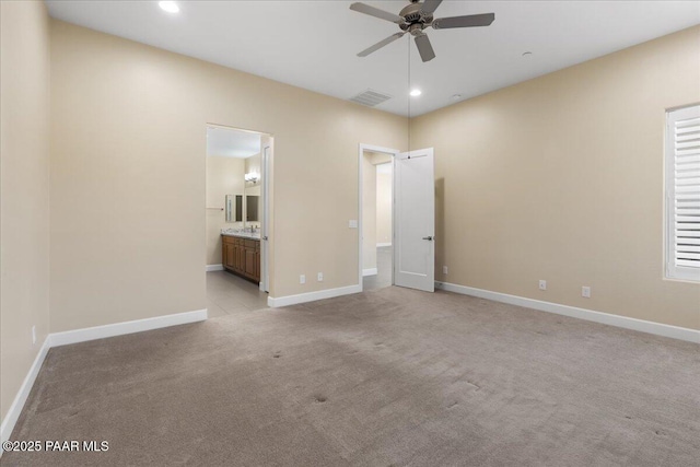 unfurnished bedroom featuring ceiling fan, light colored carpet, and ensuite bath