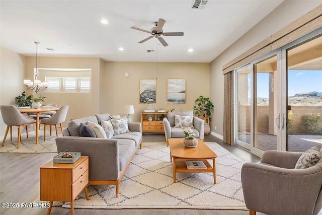 living room with ceiling fan with notable chandelier and light wood-type flooring