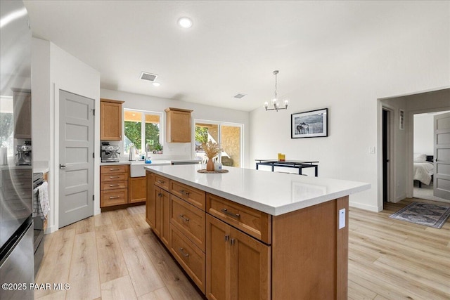 4956 E Ramada Dr, Prescott, AZ 86301 - kitchen featuring light wood-style floors, light countertops, a kitchen island, a chandelier, and hanging light fixtures