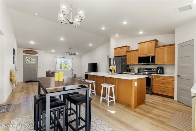 4956 E Ramada Dr, Prescott, AZ 86301 - kitchen featuring stainless steel appliances, a kitchen island, brown cabinets, light countertops, and lofted ceiling