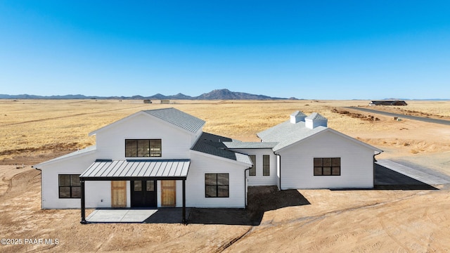 modern farmhouse style home featuring a mountain view, a patio area, and a rural view