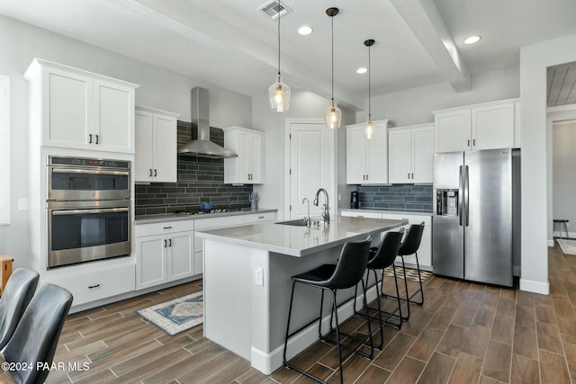 kitchen featuring wall chimney exhaust hood, hanging light fixtures, stainless steel appliances, dark hardwood / wood-style flooring, and white cabinets