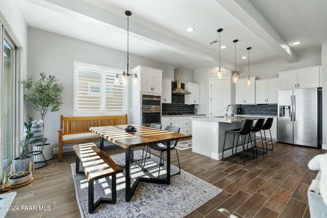 dining space with sink, beamed ceiling, dark wood-type flooring, and an inviting chandelier