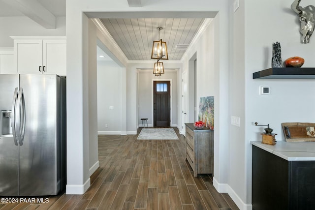 foyer with a chandelier, dark hardwood / wood-style flooring, wooden ceiling, and ornamental molding