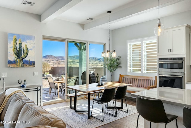 dining room featuring beam ceiling, a mountain view, dark hardwood / wood-style flooring, and a notable chandelier