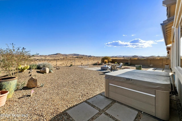 view of yard with a mountain view, a patio, and a hot tub