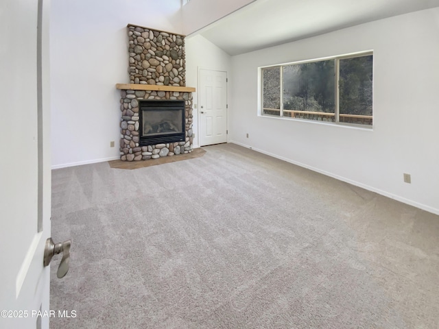 unfurnished living room featuring vaulted ceiling, carpet floors, a fireplace, and baseboards