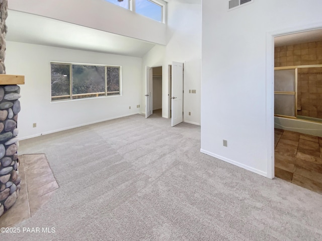 unfurnished living room featuring a high ceiling, carpet flooring, visible vents, and baseboards