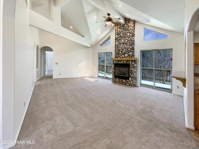 unfurnished living room featuring carpet floors, beam ceiling, a fireplace, and high vaulted ceiling
