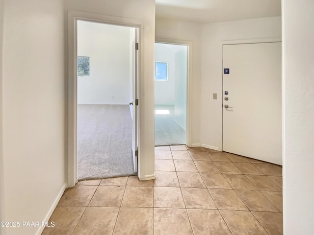 entrance foyer with light tile patterned floors, light colored carpet, and baseboards