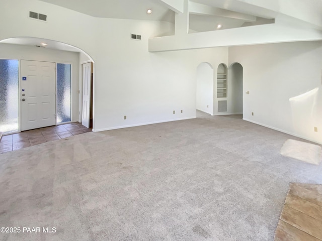 unfurnished living room with carpet, visible vents, and arched walkways