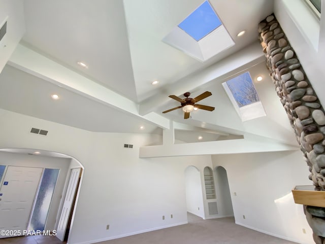 carpeted living room with arched walkways, recessed lighting, visible vents, baseboards, and lofted ceiling with skylight
