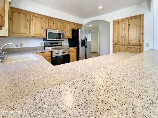 kitchen with arched walkways, stainless steel appliances, a sink, and recessed lighting