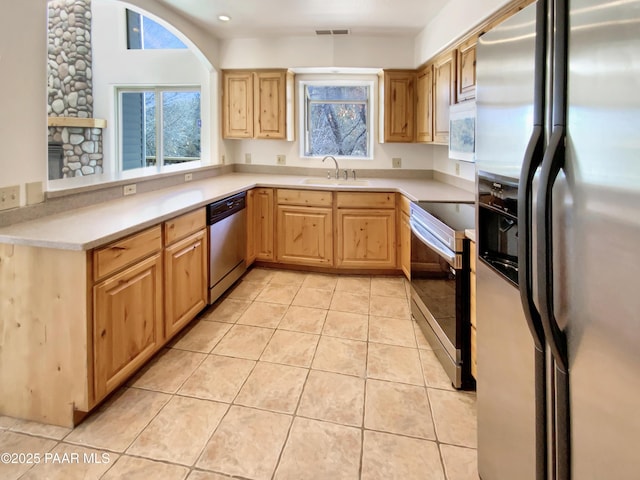 kitchen with stainless steel appliances, light countertops, visible vents, light tile patterned flooring, and a sink