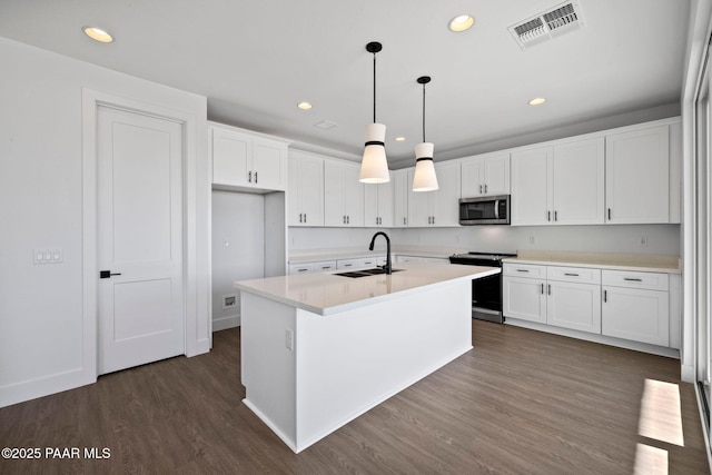 kitchen with appliances with stainless steel finishes, sink, a center island with sink, white cabinetry, and hanging light fixtures