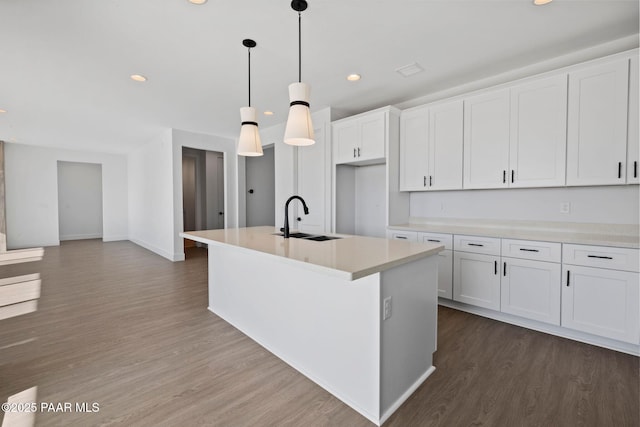 kitchen featuring hardwood / wood-style floors, a kitchen island with sink, sink, hanging light fixtures, and white cabinetry