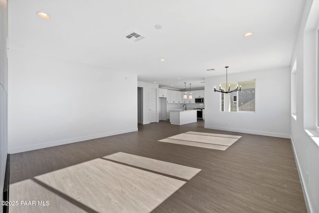 unfurnished living room with a chandelier and dark hardwood / wood-style floors