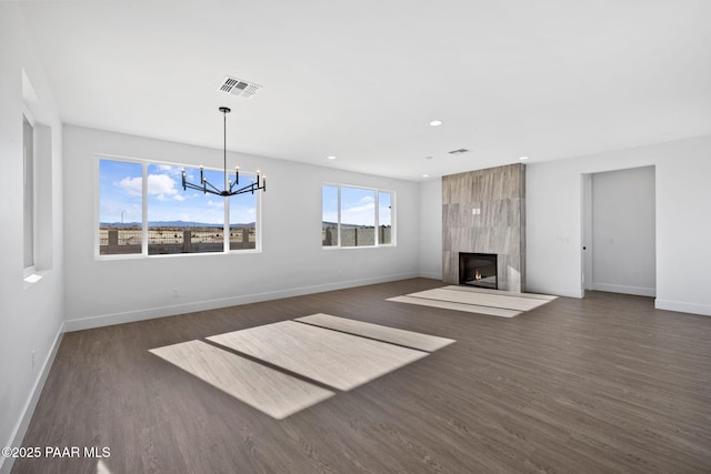 unfurnished living room featuring a notable chandelier, dark hardwood / wood-style flooring, and a fireplace