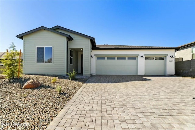 view of front of home with a shingled roof, a garage, and decorative driveway