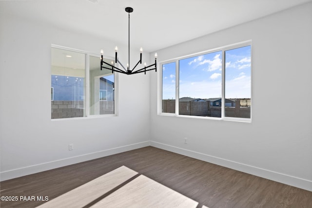 unfurnished dining area featuring dark hardwood / wood-style flooring and an inviting chandelier