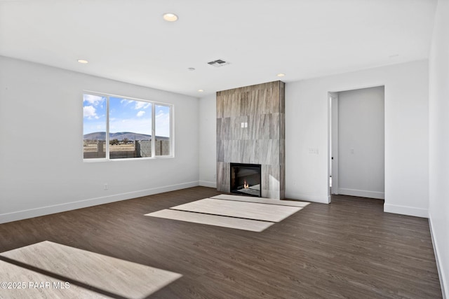 unfurnished living room with a mountain view, a high end fireplace, and dark hardwood / wood-style floors