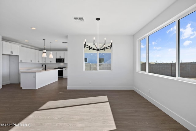 kitchen featuring hanging light fixtures, white cabinetry, a center island with sink, and stainless steel appliances