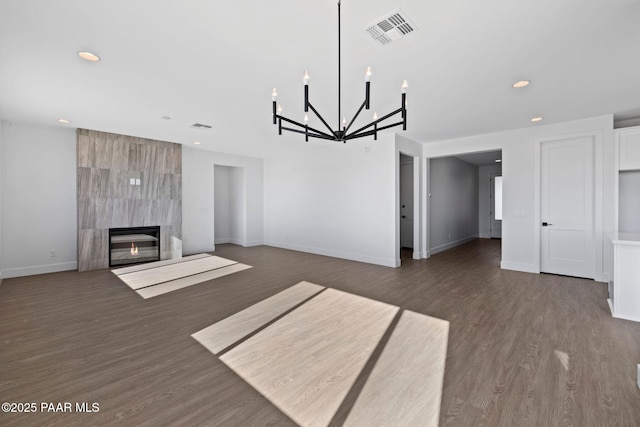 unfurnished living room with dark hardwood / wood-style floors, a high end fireplace, and an inviting chandelier