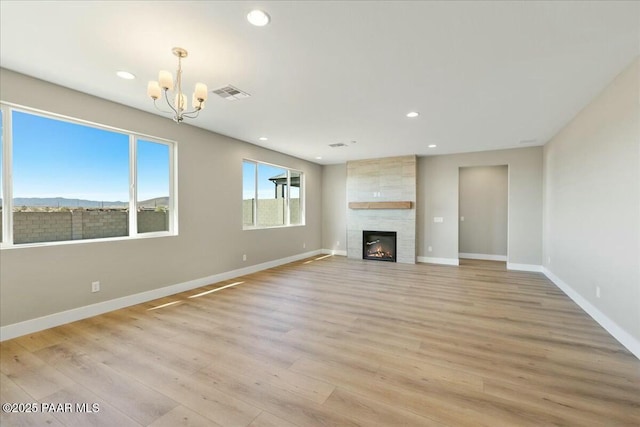 unfurnished living room with visible vents, a chandelier, baseboards, wood finished floors, and recessed lighting
