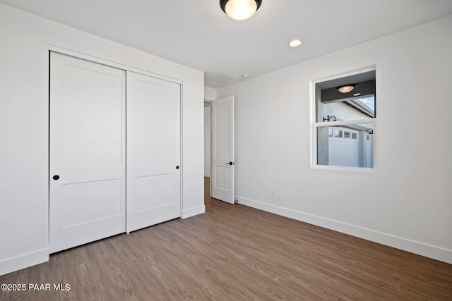 unfurnished bedroom with hardwood / wood-style floors and a closet