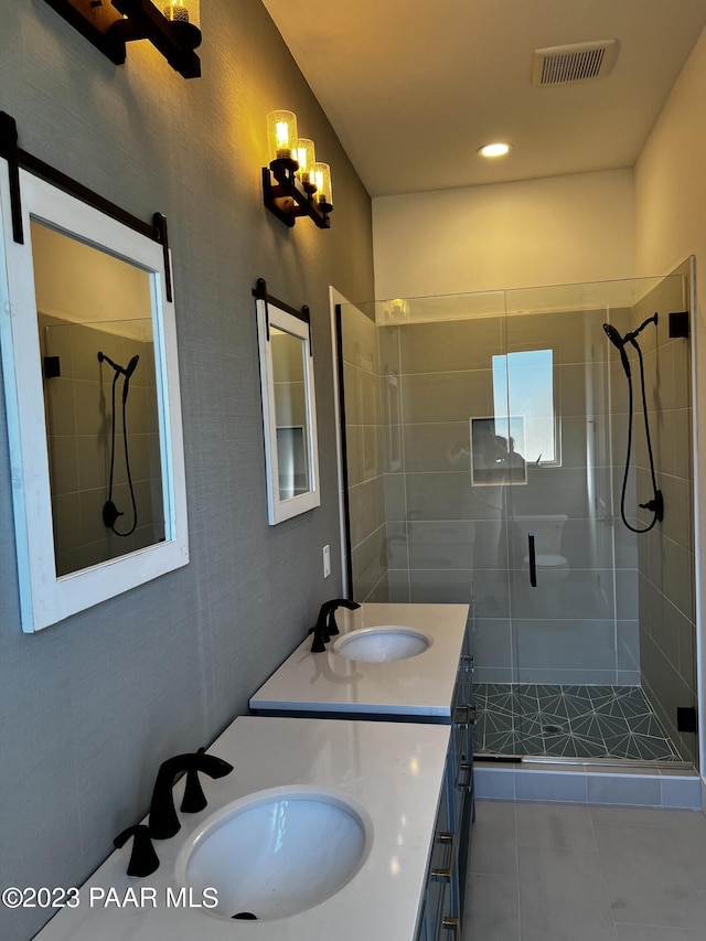 bathroom with double vanity, a shower stall, visible vents, and a sink