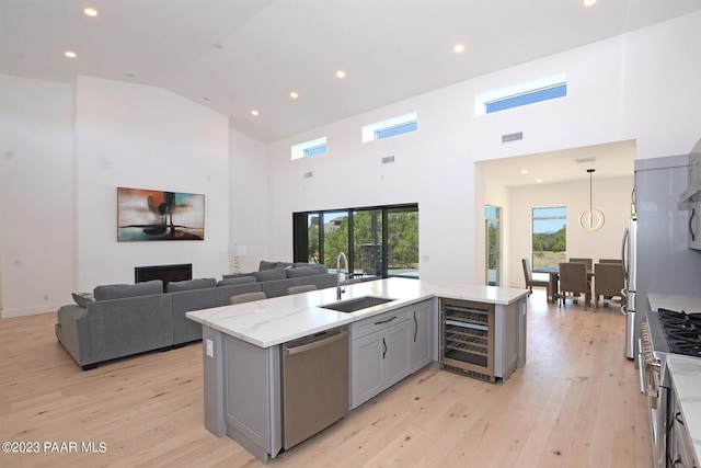 kitchen featuring wine cooler, stainless steel appliances, gray cabinetry, light wood-style floors, and a sink