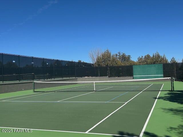 view of tennis court with community basketball court and fence