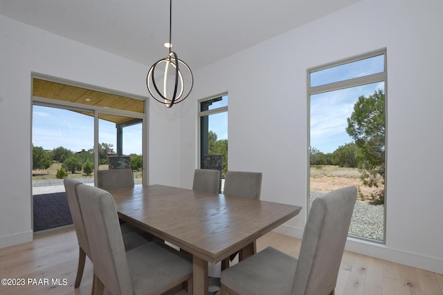 dining space featuring light wood-style floors, baseboards, and an inviting chandelier